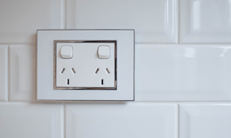 A photograph of a dual power socket on white tiles.