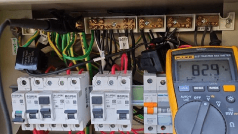 A photograph of voltage tested on the Back Up Neutral Bar. The tester display reads 