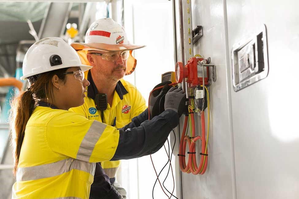 Electrician and apprentice work at a switchboard