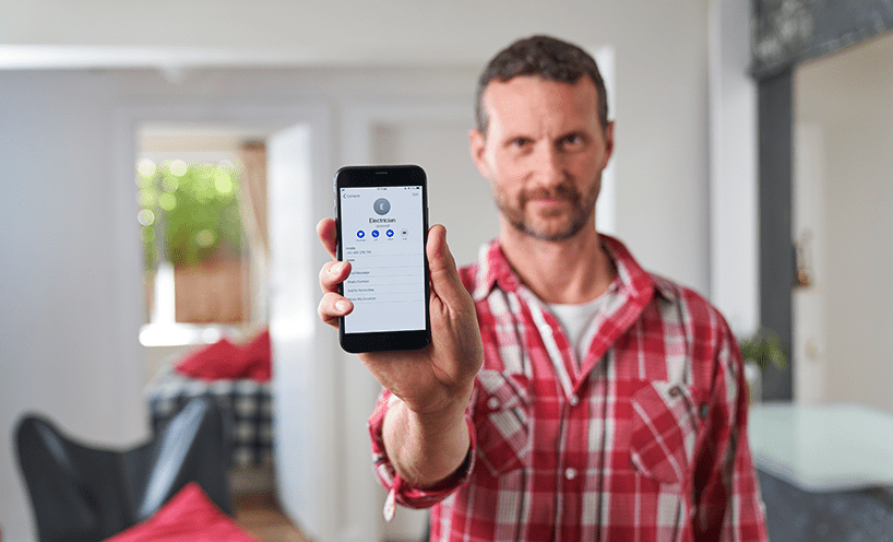 A person holds up a mobile phone to show how easy it is to find and hire an electrician