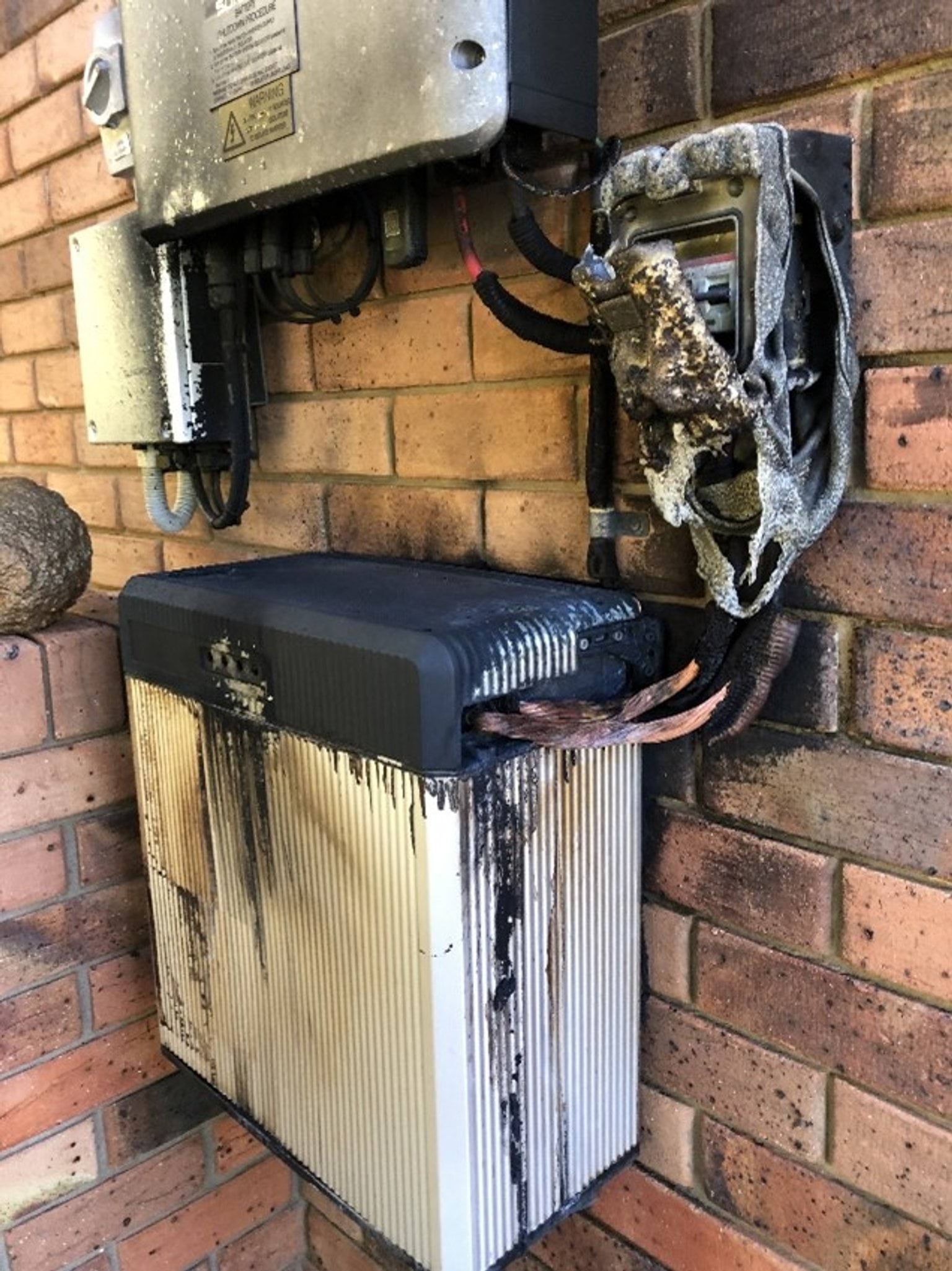 A photograph of a solar battery that has caught fire, with burn marks and melted components.