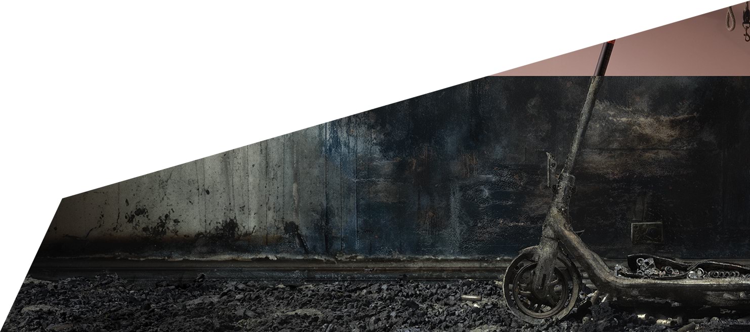 A photograph of a burnt scooter in a burnt down room of a house.