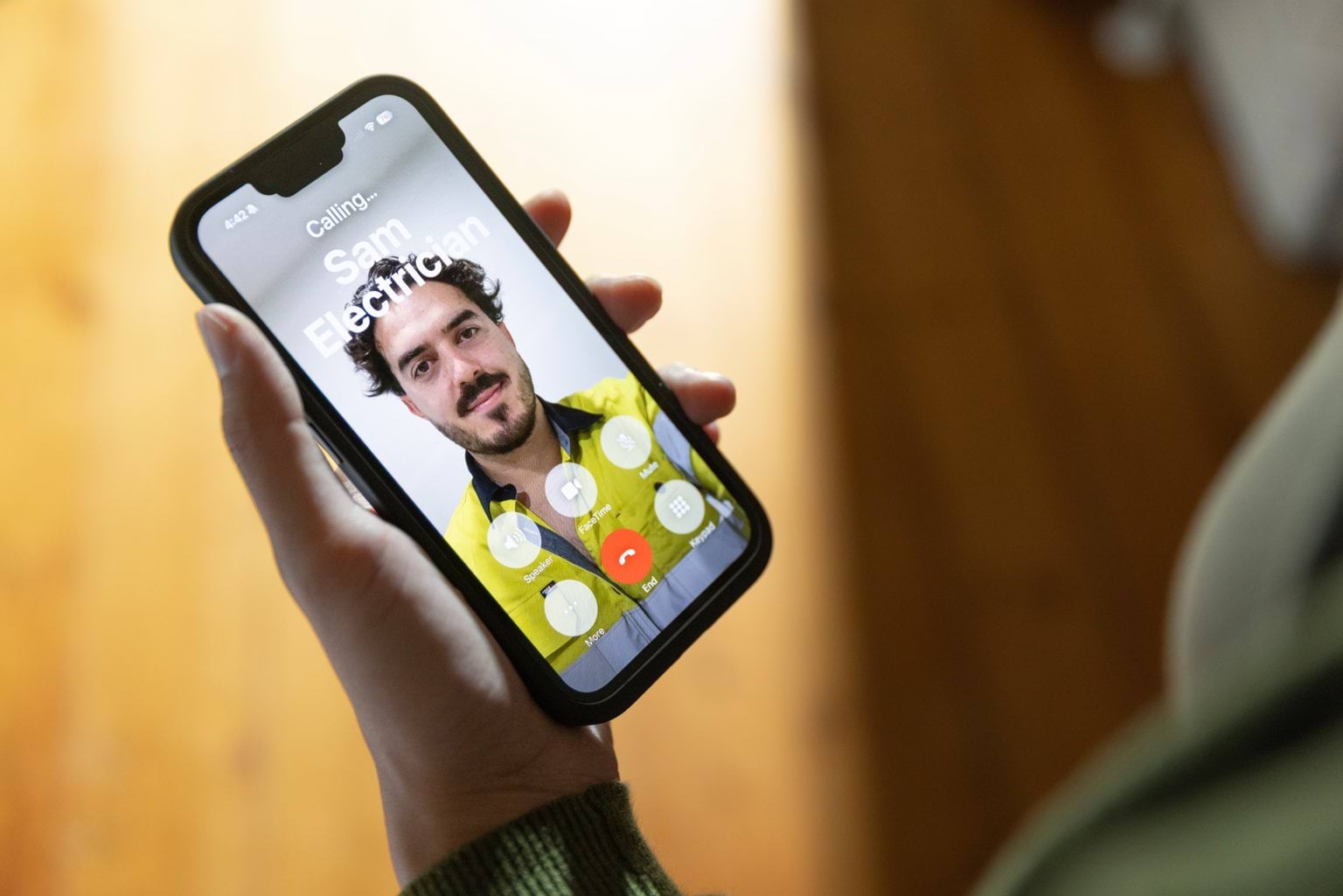 A person calling a licensed electrician on a smart phone.