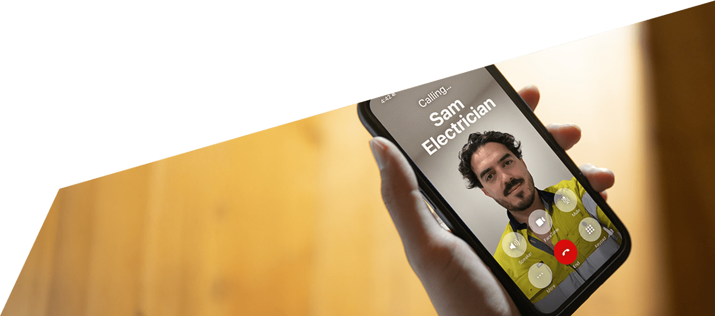 A hand holding a mobile phone with an electrician on the screen.